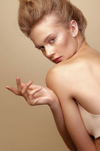 Portrait of young woman with eye make-up against brown background