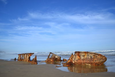 Shipwreck at beach against sky