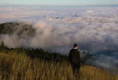 High angle view of man standing on mountain against cloudscape