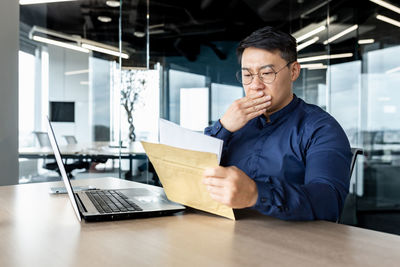 Side view of young man using digital tablet while sitting in office