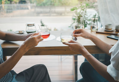 Midsection of woman holding drink while sitting on table