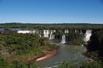 Scenic view of waterfall against clear blue sky