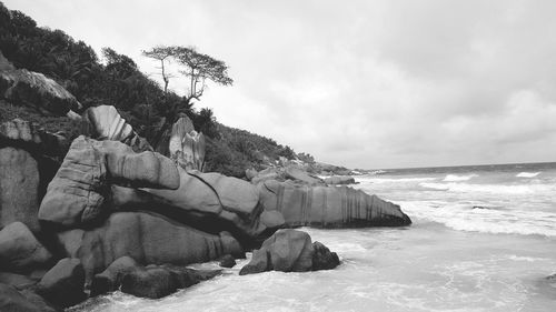 View of rocky beach against cloudy sky