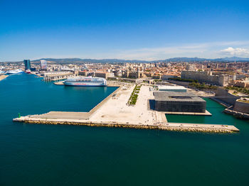 High angle view of city by sea against blue sky