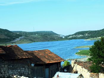 Scenic view of lake and mountains against sky seen from village