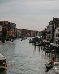 Boats in canal amidst buildings in city against sky