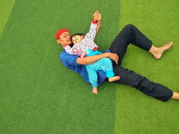 High angle view of father and son lying on grass outdoors