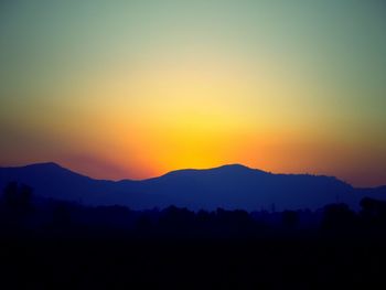 Scenic view of silhouette mountains against orange sky