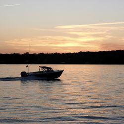 Boat sailing in sea at sunset