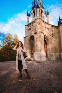 Woman standing by building against sky