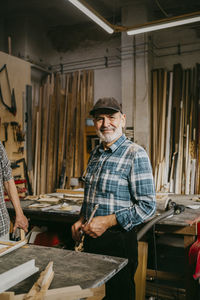 Portrait of smiling senior craftsman standing at workshop