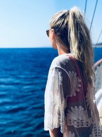 Side view of woman looking at sea while standing on sailboat