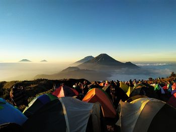 Group of people camping on mountain against sky during sunset