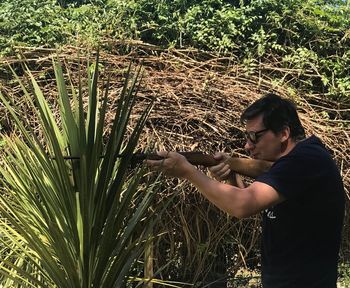 Side view of man holding plants on field