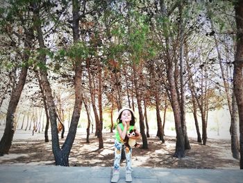 Portrait of woman standing by trees in forest