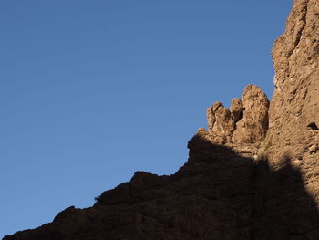 Low angle view of rock formation against clear blue sky