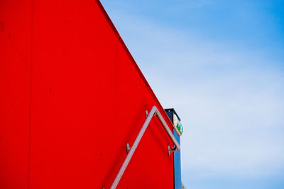 Low angle view of railing on red wall against sky