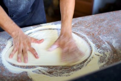 Midsection of man flattening dough in kitchen