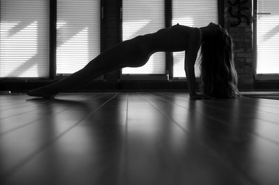 Woman exercising on hardwood floor at home