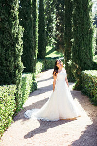 Happy bride standing on footpath in park during sunny day