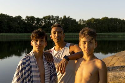 Portrait of father standing with sons on vacation during sunset