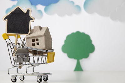 Close-up of model home in miniature shopping cart against white background