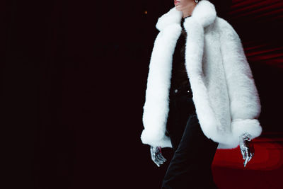 Fashion details white fluffy winter fur coat and silver gloves. fashion model on black background