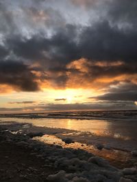 Scenic view of sea against dramatic sky during sunset