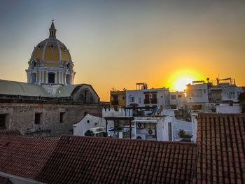 Buildings in city against sky during sunset
