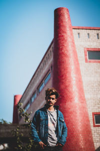 Low angle view of man standing against building and sky