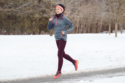 Full length of woman jogging on road during winter