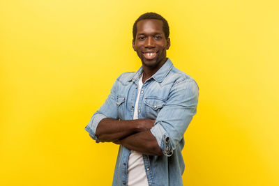 Portrait of smiling young man against yellow background
