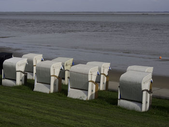 Hooded chairs on beach against sky