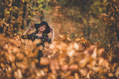 Portrait of young woman standing on field during autumn