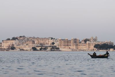 People on boat in sea against buildings in city