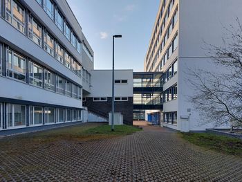 Street by modern buildings against sky in city