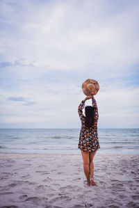 Full length of woman standing on beach against sky