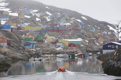 Scenic view of town by mountain against sky