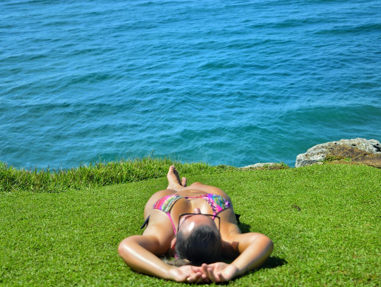 water, sea, leisure activity, lifestyles, grass, relaxation, sitting, person, high angle view, tranquility, tranquil scene, nature, beauty in nature, horizon over water, men, blue, sunlight, relaxing