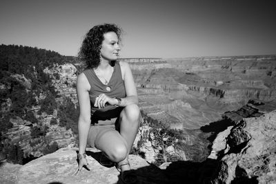 Young woman looking away while sitting on rock