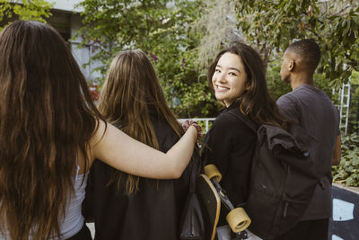 Smiling young woman looking back while walking with friends in city