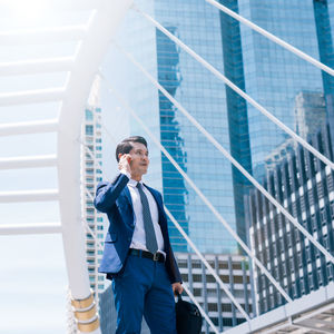 Businessman answering smart phone while standing in city