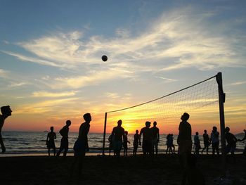 Silhouettes of people playing beach volleyball