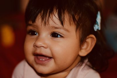 Close-up of cute baby girl looking away at home