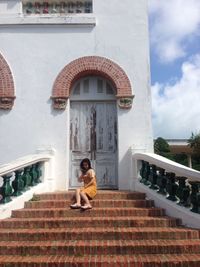 Portrait of woman sitting on staircase against building