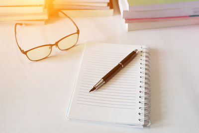 Close-up of pen on open blank book at table