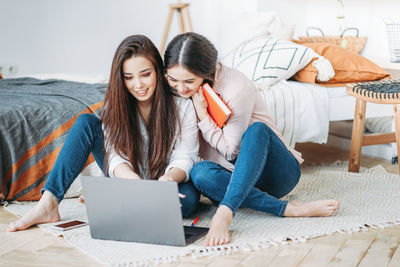 Friends discussing over laptop while relaxing at home