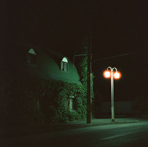 Illuminated street light against building at night