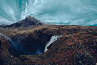 Scenic view of  waterfall and mountains against sky