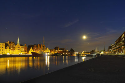 Illuminated buildings by river at night